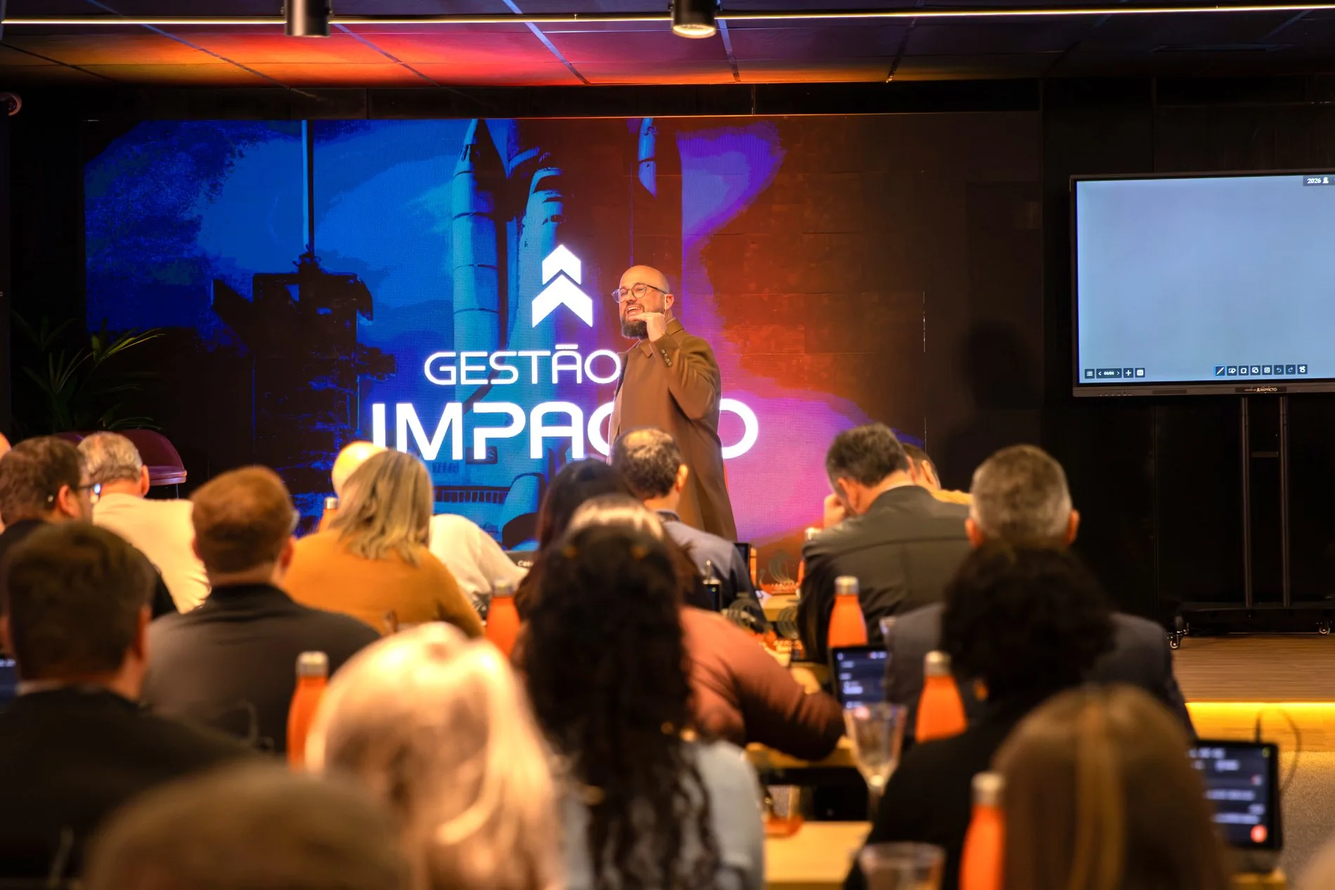 Ítalo Rickes no palco diante de uma sala cheia de empresários em evento da Gestão de Impacto